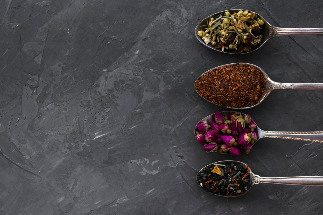 Close-up of dried herbal tea ingredients — dried flowers, leaves and spices arranged on a dark surface